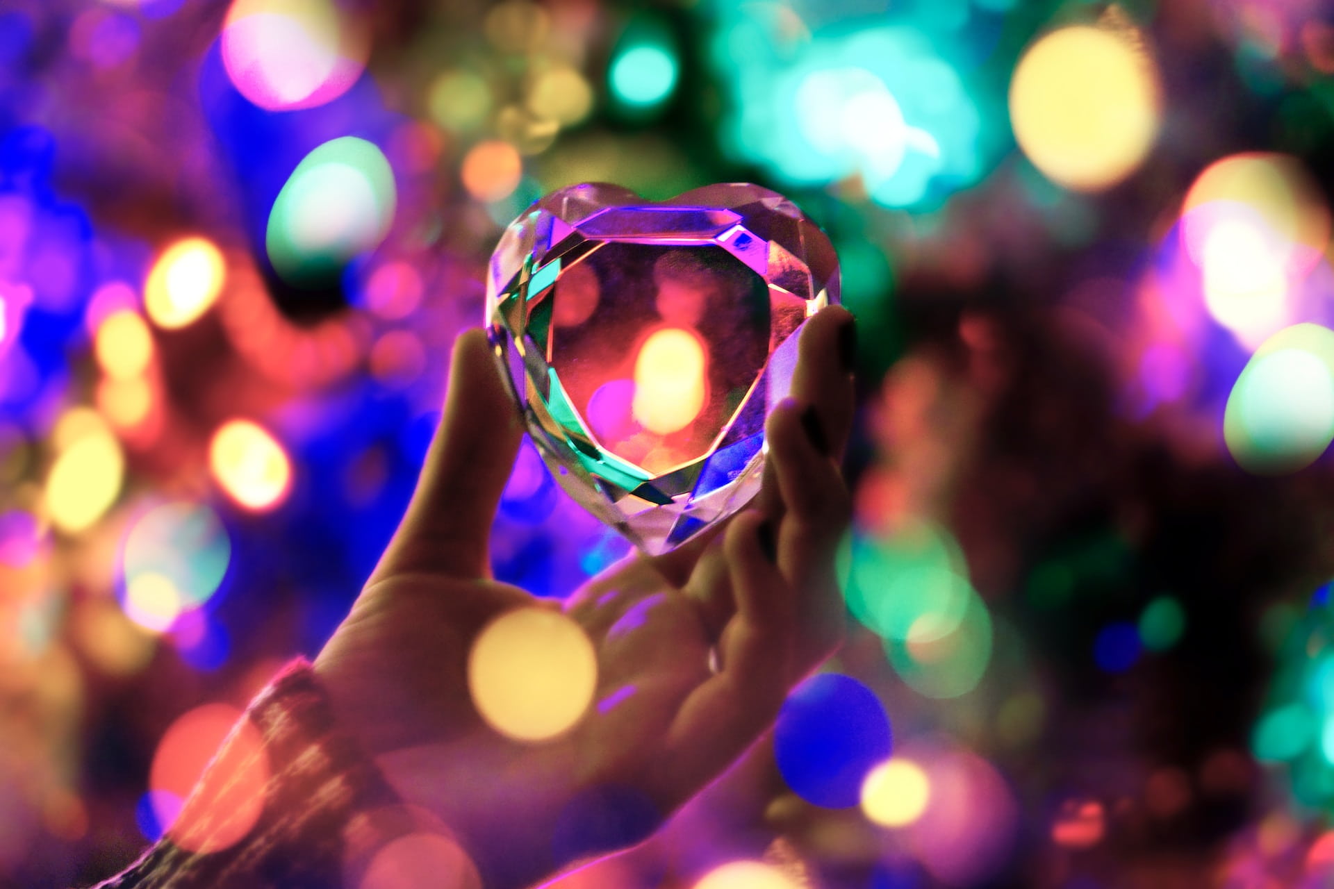 Crystal heart held with colorful light orbs all around.